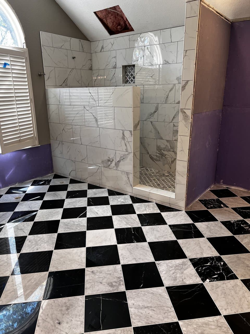 Black and white checkerboard marble floor with walk-in shower