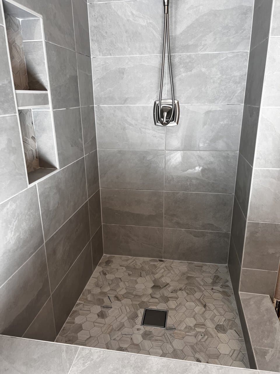 Gray porcelain shower with hexagon mosaic floor and built-in niche