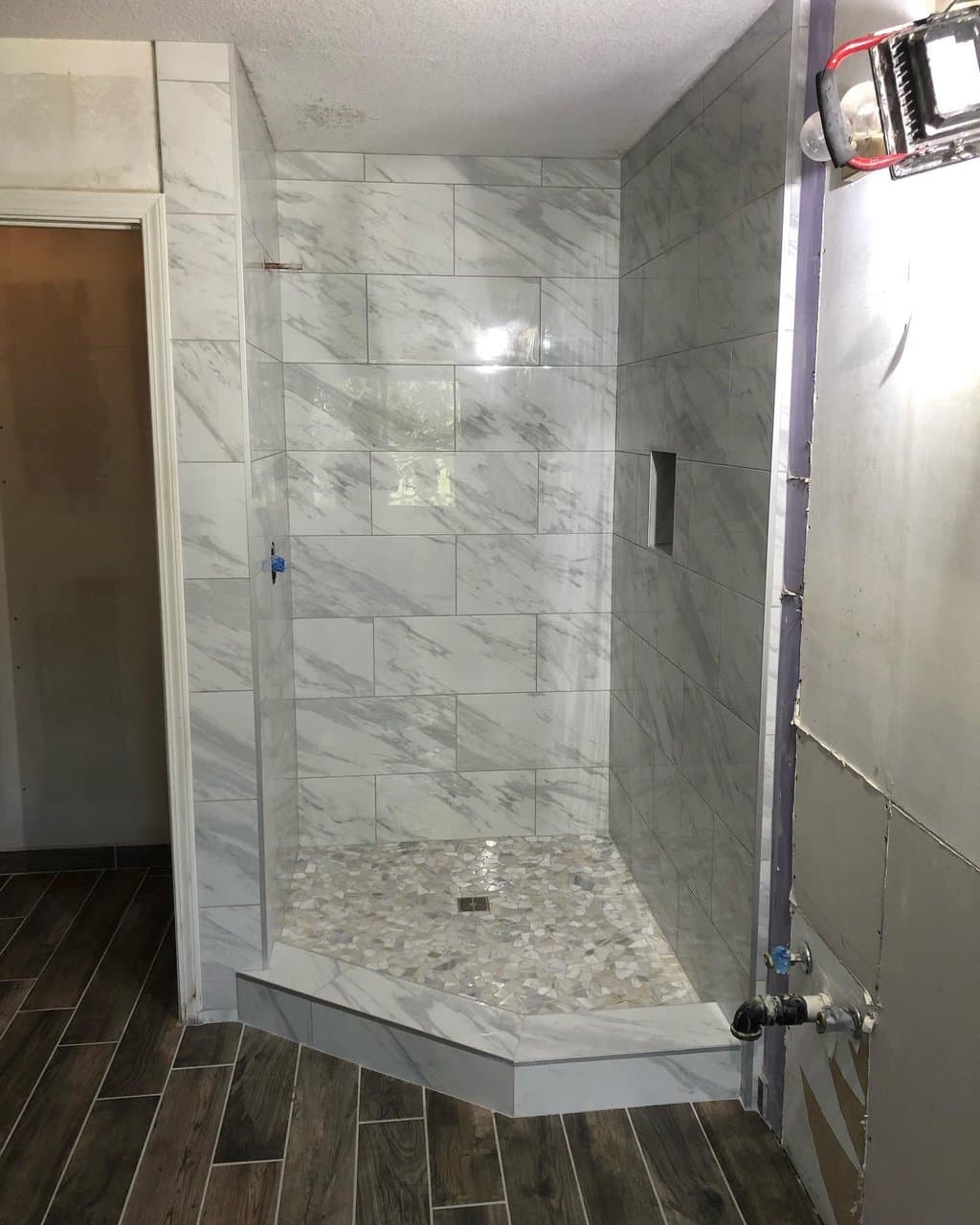 Marble-look tile shower with mosaic shower pan and wood-look floor