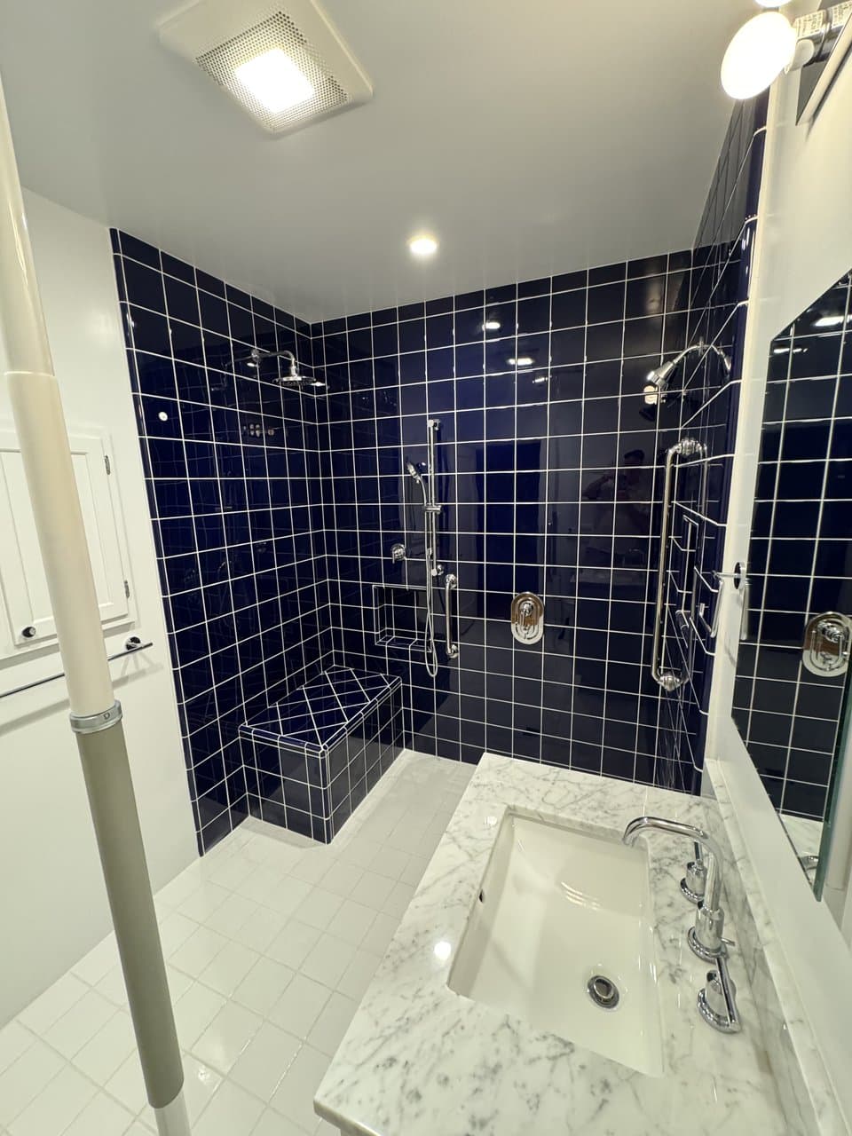 Navy tile shower with marble countertop vanity and chrome fixtures