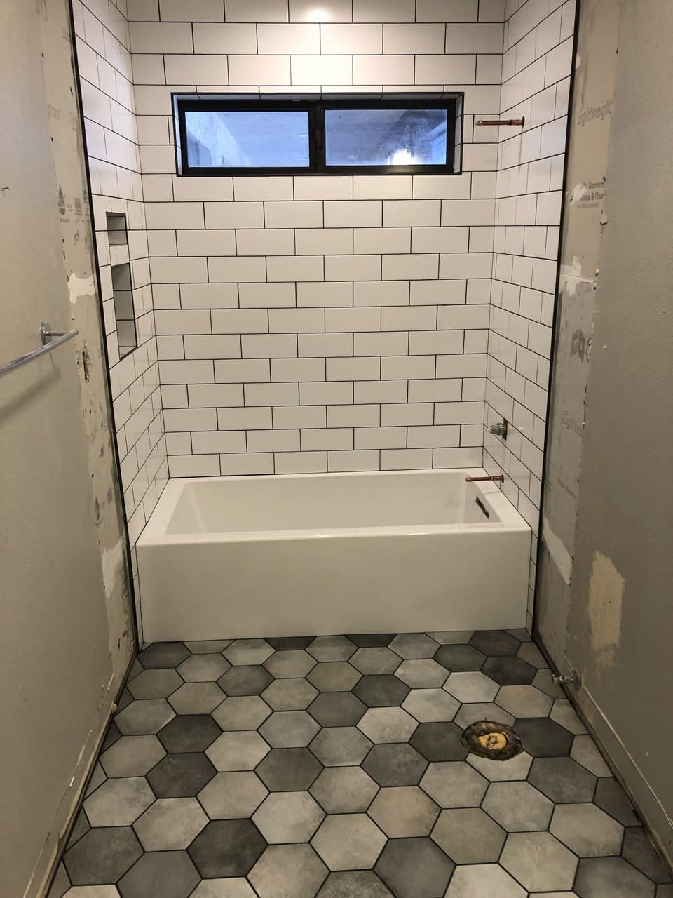 Tub-shower combo with white subway tile walls and gray hexagon floor