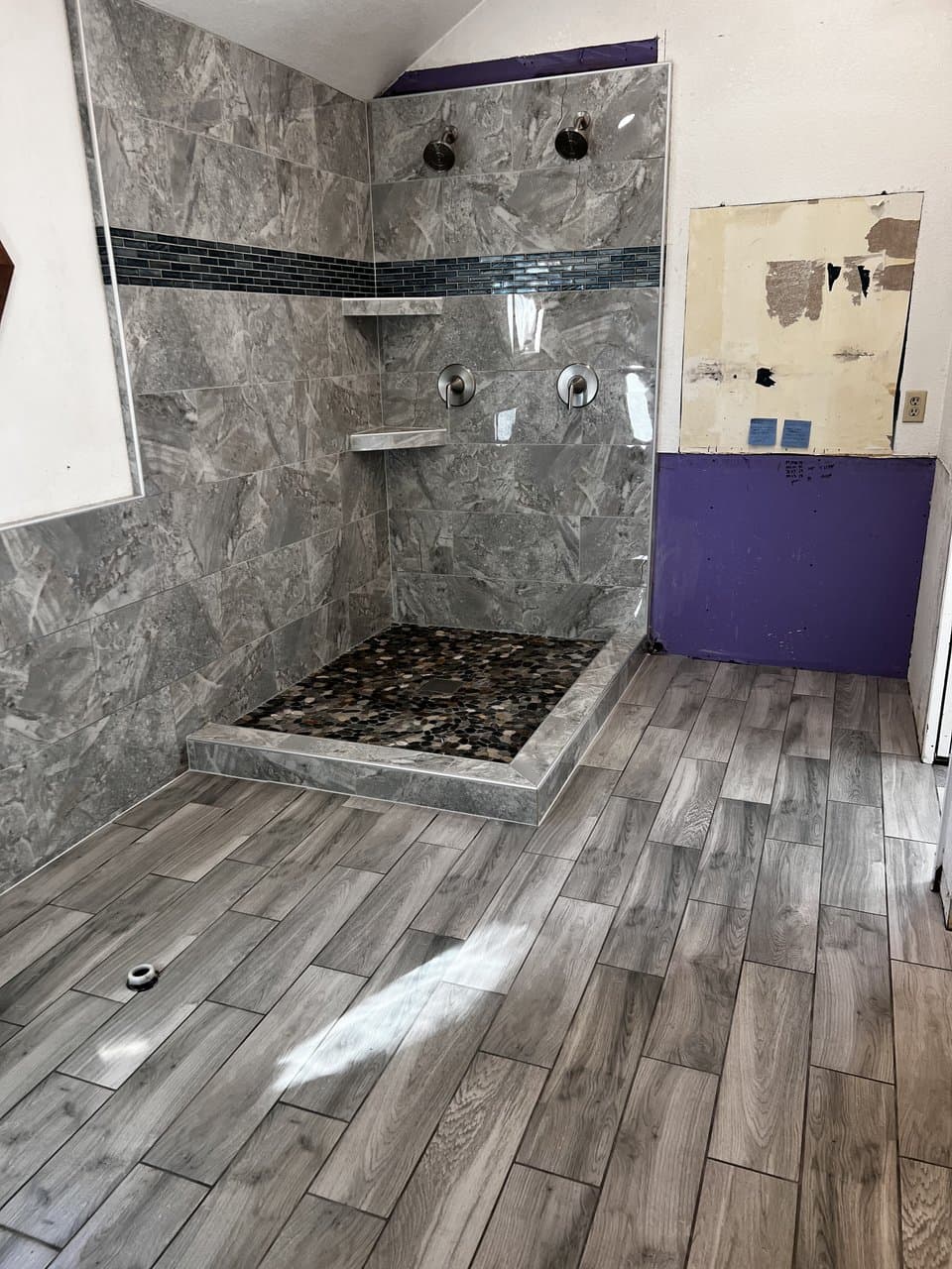 Wood-look tile flooring with stone tile shower and accent band